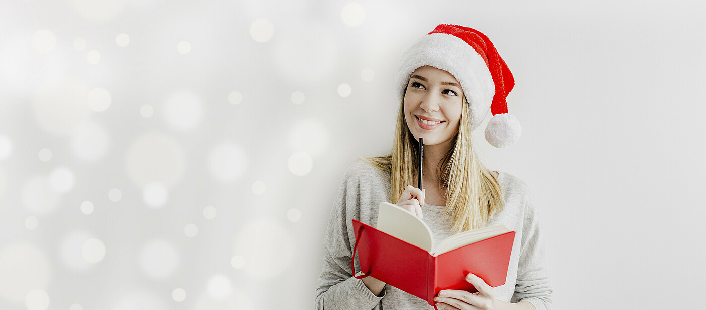 Mädchen mit Weihnachtsmütze, Stift und Buch