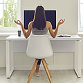 Schülerin von hinten sichtbar am Schreibtisch sitzend mit Yoga-Armstellung.