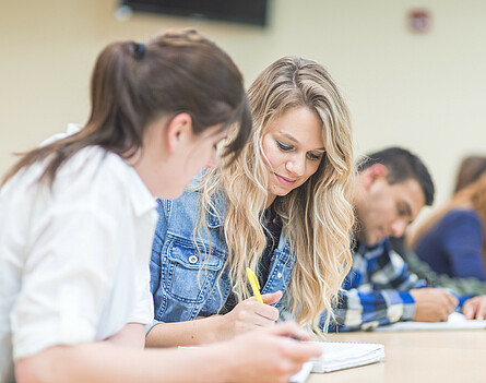 Oberstufenschüler*innen in einer Sitzreihe beim Schreiben