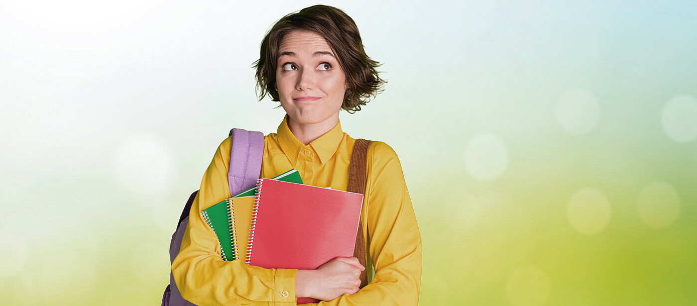 Schülerin mit Schulsachen, im Hintergrund eine Frühlingswiese