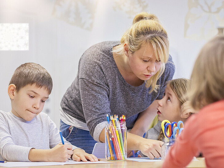 Eine Lehrkraft unterstützt Volksschulkinder beim Lernen