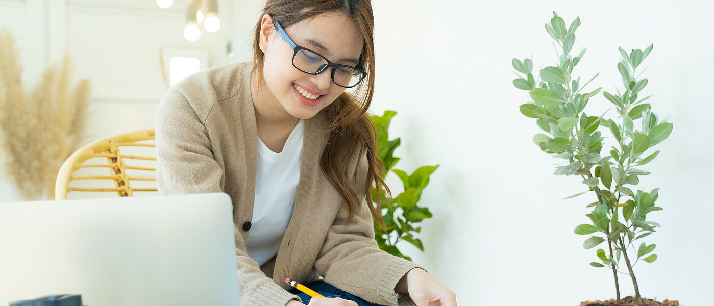 Oberstufenschülerin sitzt an einem Gartentisch und schreibt
