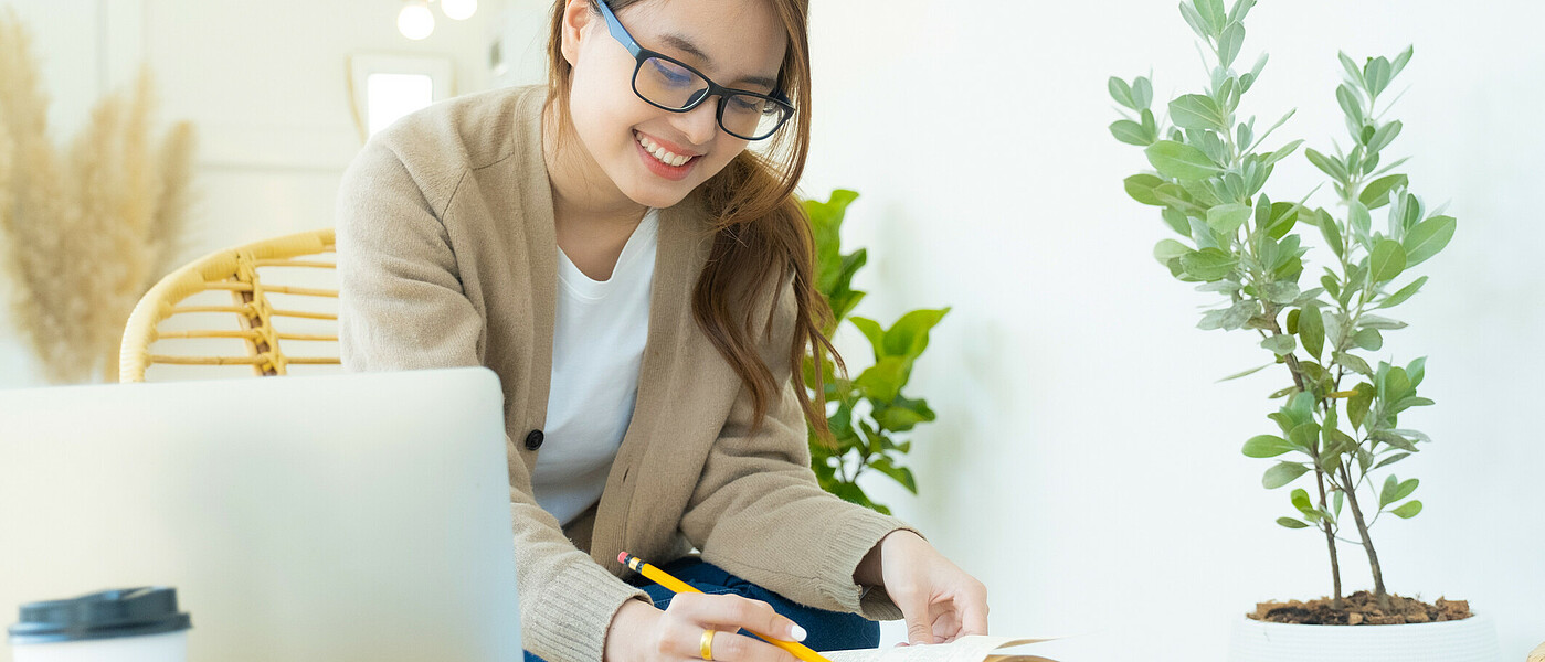Oberstufenschülerin sitzt an einem Gartentisch und schreibt