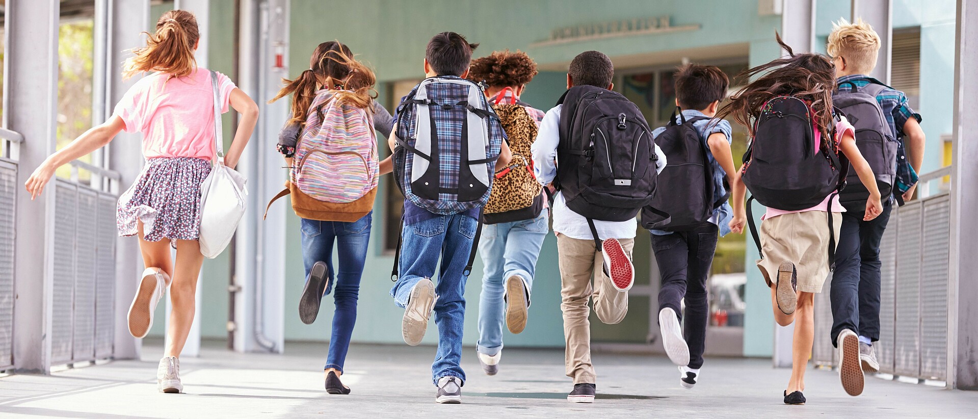 Schulkinder mit Rucksäcken laufen am Gang entlang