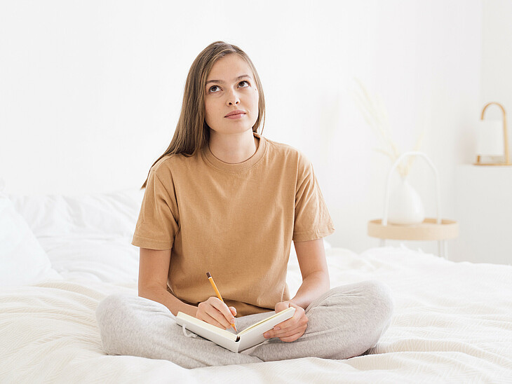 Eine Schülerin sitzt am Abend mit einem Buch im Bett und wiederholt das untertags Gelernte