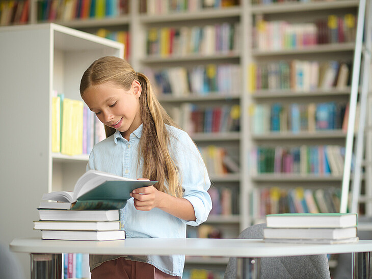 Eine Schülerin steht an einem Pult mit Büchern und lernt im Stehen
