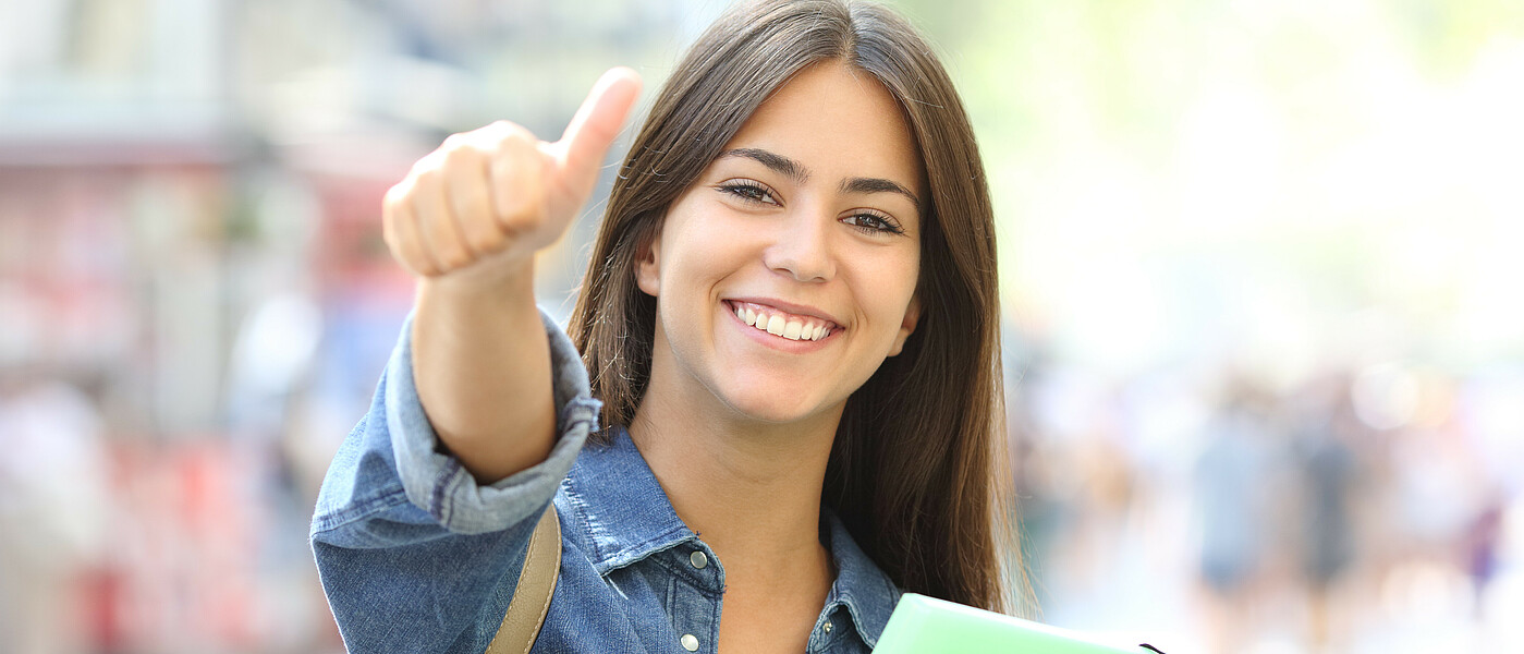 Schülerin auf der Straße mit erhobenen Daumen.
