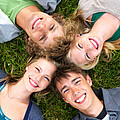 Vier Schüler*innen liegen im Gras und schauen in die Kamera