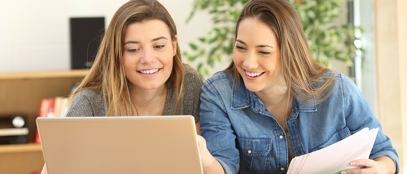 Zwei Schülerinnen sitzen vor dem Laptop