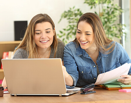 Zwei Schülerinnen sitzen vor dem Laptop
