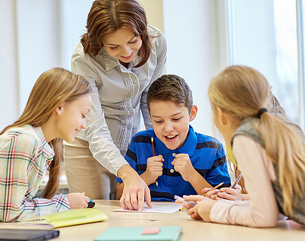 zwei Schülerinnen und ein Schüler mit einer Lehrkraft