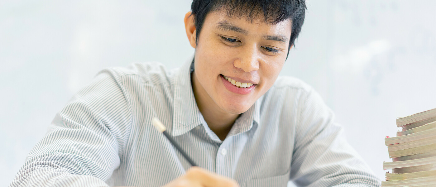 Schüler sitzt beim Tisch und schreibt