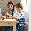Eltern mit zwei Kindern sitzen beim Tisch und lernen