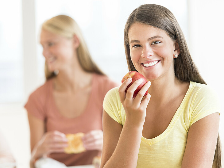 Lernfit – Brainfood – LernQuadrat Nachhilfe Eine Schülerin mit ihren Freunden in der Pause mit einem Apfel