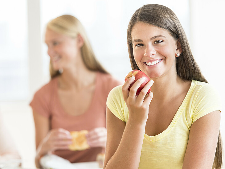 Lernfit – Brainfood – LernQuadrat Nachhilfe Eine Schülerin mit ihren Freunden in der Pause mit einem Apfel
