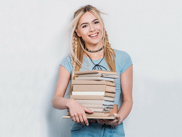 Eine Schülerin übersiedelt und trägt einen Stapel eingepackter Bücher