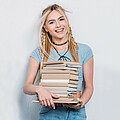 Eine Schülerin übersiedelt und trägt einen Stapel eingepackter Bücher