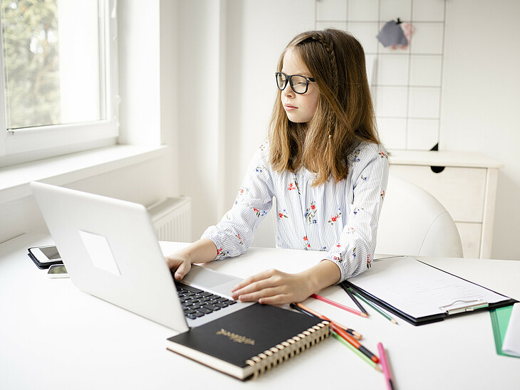 Aufrecht sitzende Schülerin lernt und arbeitet am Laptop