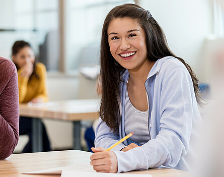 Oberstufenschülerin sitzt beim Tisch und schreibt