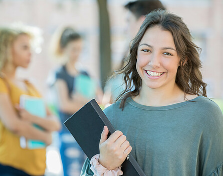 lächelnde Schülerin mit Buch in der Hand