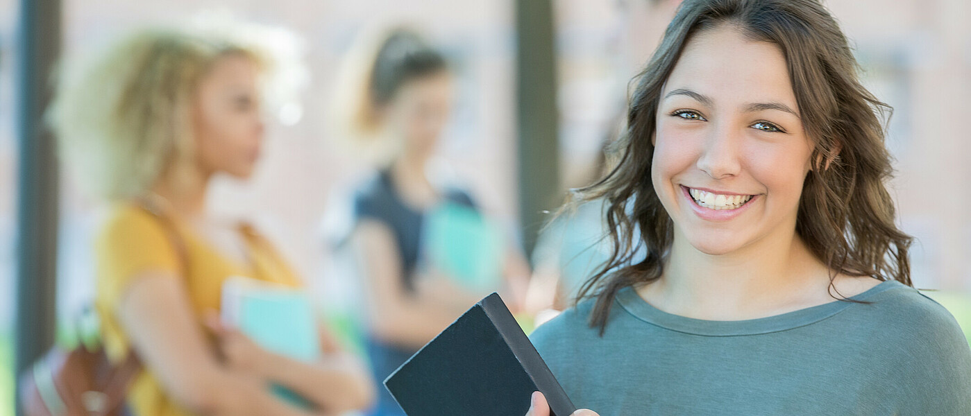 lächelnde Schülerin mit Buch in der Hand