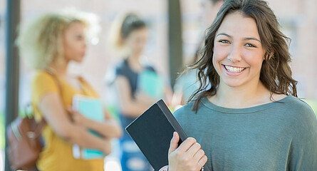 lächelnde Schülerin mit Buch in der Hand