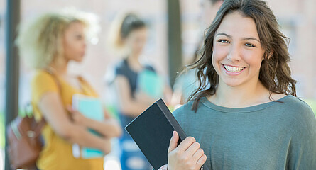 lächelnde Schülerin mit Buch in der Hand