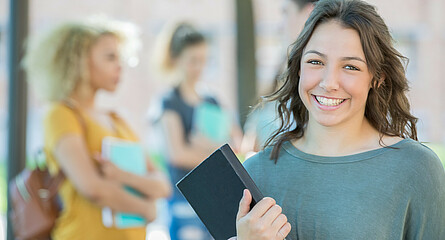 lächelnde Schülerin mit Buch in der Hand